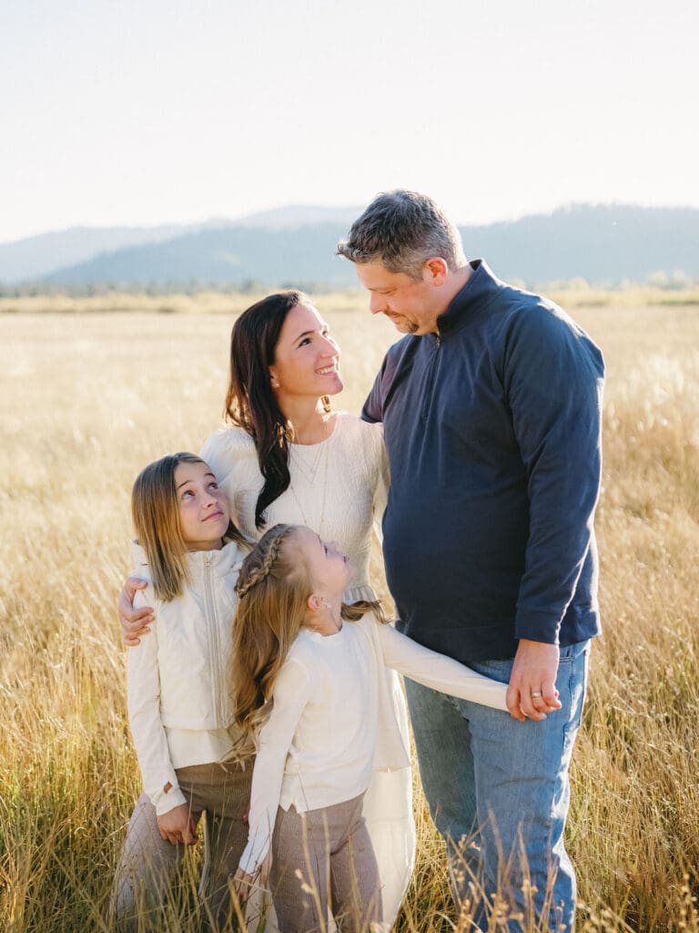 A family poses together in a scenic field during their photo session in South Lake Tahoe, capturing joyful moments.
