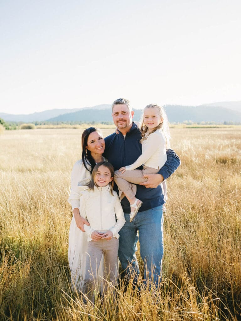 A family poses together in a scenic field during their photo session, capturing joyful moments.
