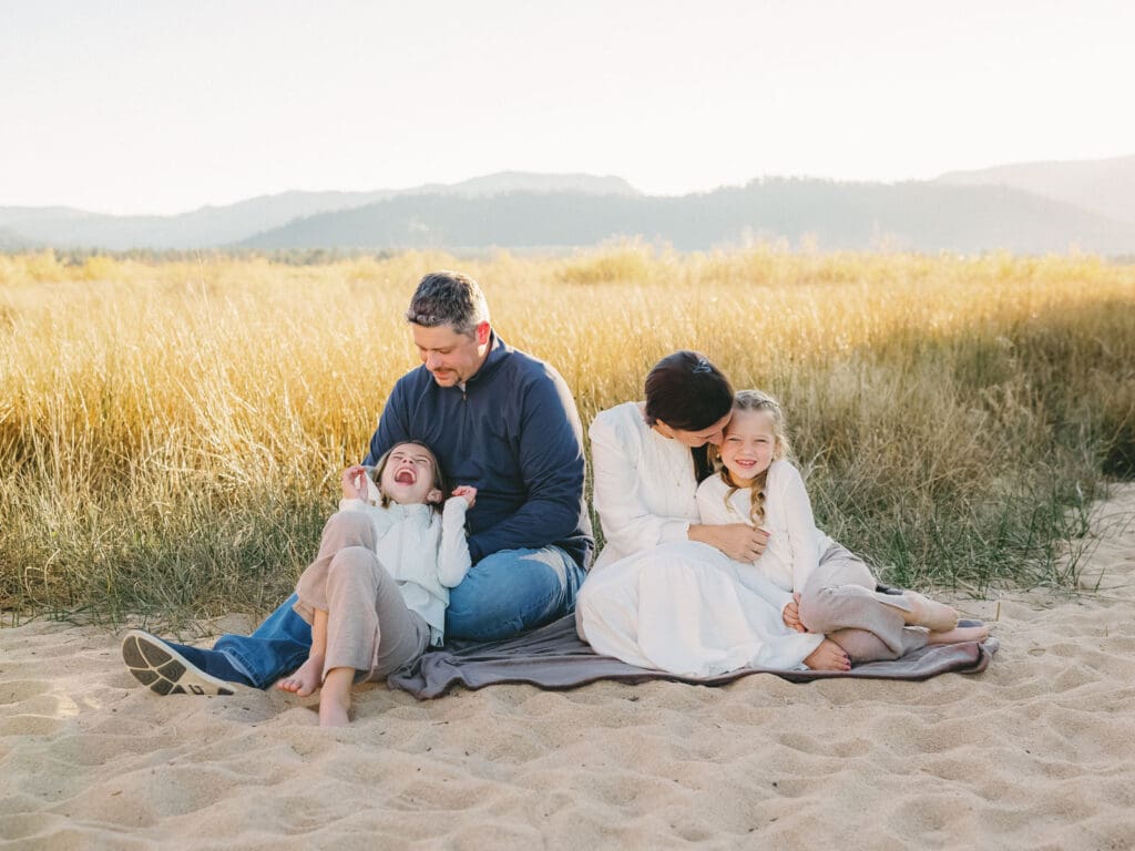 A family poses together in a scenic field during their photo session, capturing joyful moments.